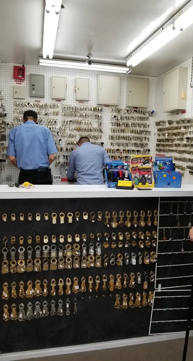 Two Mount's locksmiths at the key-blank wall behind the counter